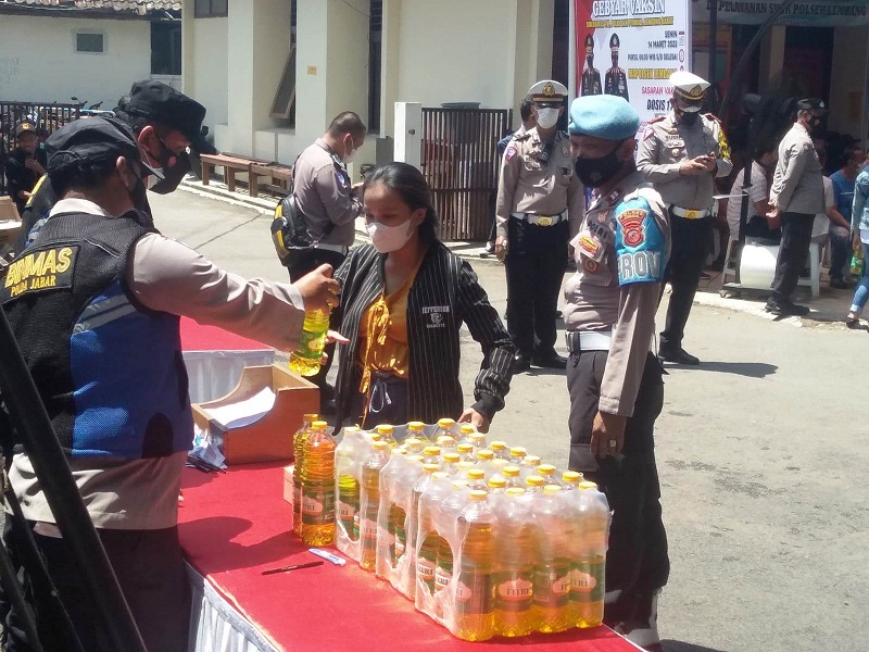 VAKSINASI: Petugas kepolisian memberikan minyak goreng kemasan kepada warga yang sudah mengikuti vaksinasi Covid-19 di Mapolsek Lembang, Senin (14/3).
