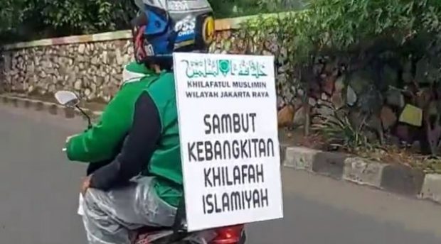 KONVOI : Salah seorang anggota Khilafatul Muslimin membagikan selebaran kepada pengendara pada aksi konvoi di sekitar jalan Parongpong dan Cisarua wilayah Bandung Barat, Minggu (29/5). Ilustrasi