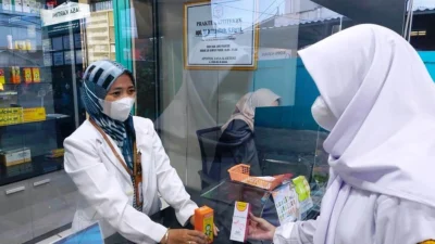 PELAYANAN: Apoteker Ai Istiklaliah, S.Farm, Apt, selaku Kepala Apotek Jasa Kartini saat menyerahkan obat langsung kepada Pasien